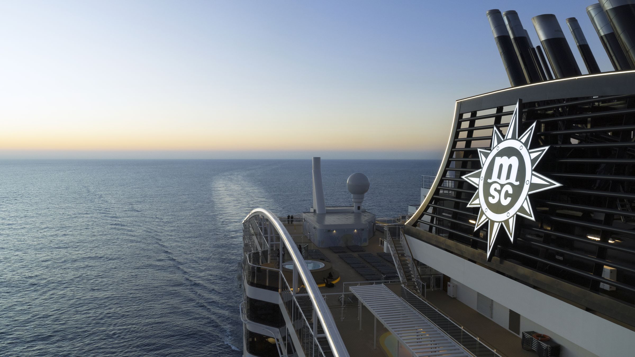 Deck superior e chaminé do MSC World Europa ao entardecer, em alto-mar